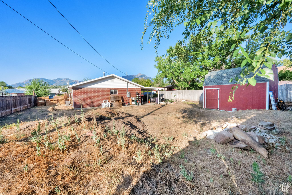 Fenced backyard featuring a mountain view and a storage shed