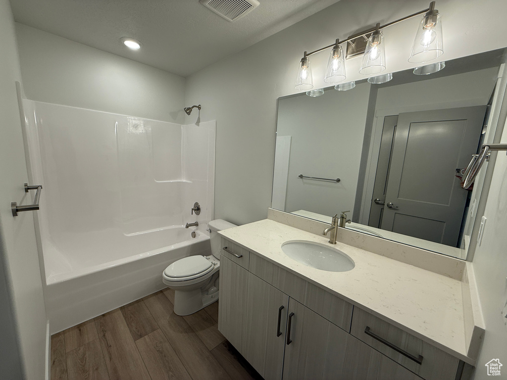 Bathroom featuring wood finished floors, vanity, shower / tub combination, and recessed lighting