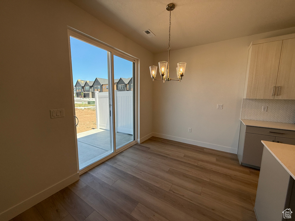 Unfurnished dining area with a chandelier and wood finished floors