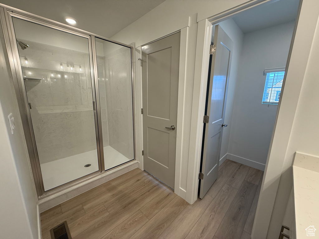 Full bathroom with wood finished floors, a stall shower, and recessed lighting