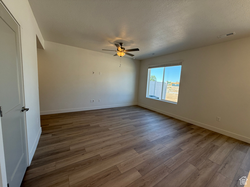 Unfurnished room featuring wood finished floors, a ceiling fan, and a textured ceiling
