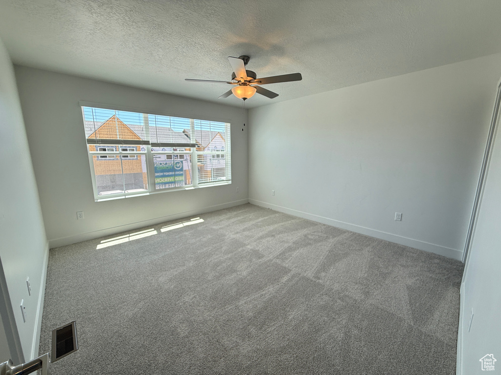 Carpeted spare room featuring a ceiling fan and a textured ceiling