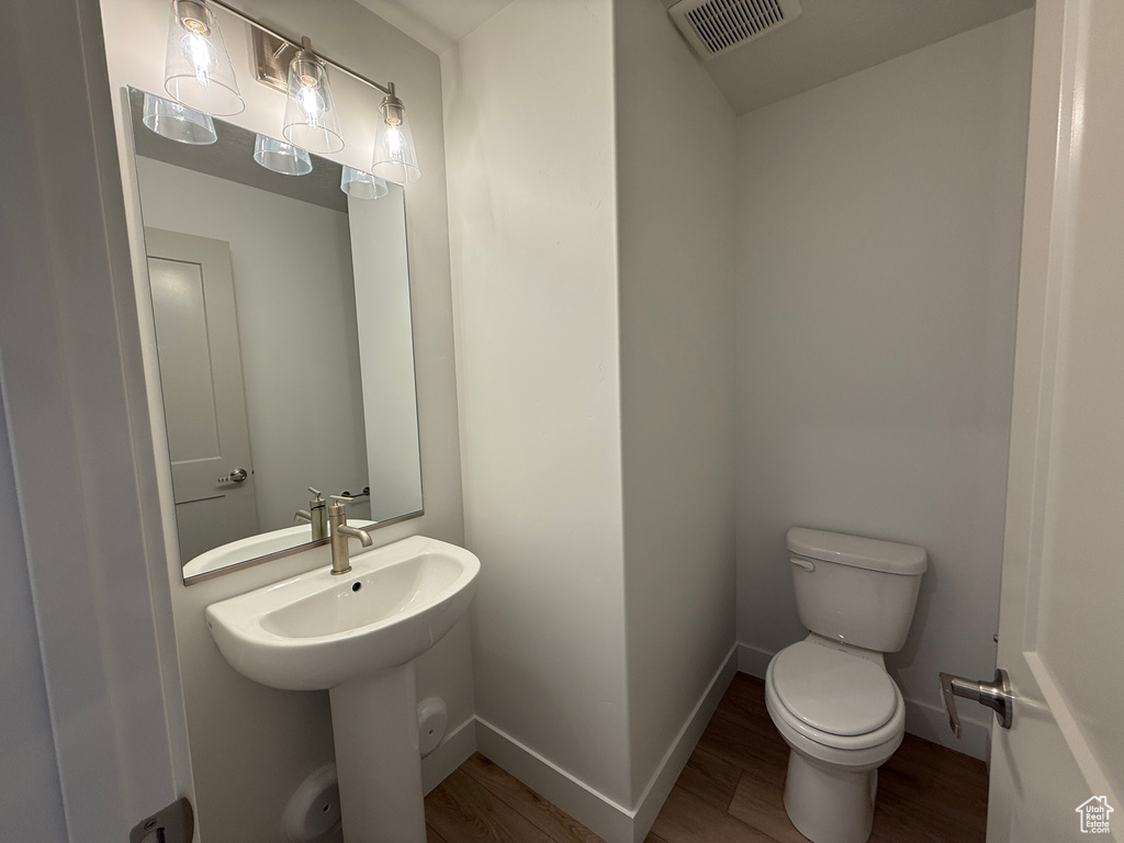 Half bathroom featuring wood finished floors and toilet