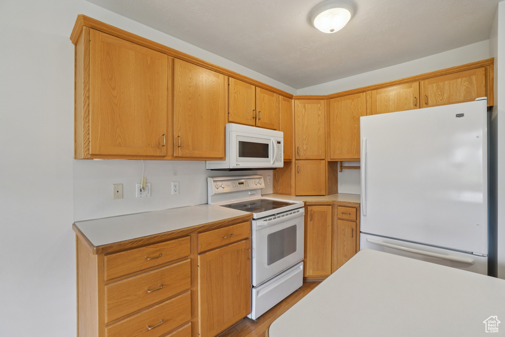 Kitchen with white appliances, light countertops, and wood finished floors