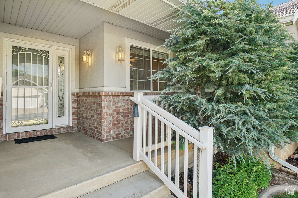 Property entrance with brick siding, covered porch, and stucco siding