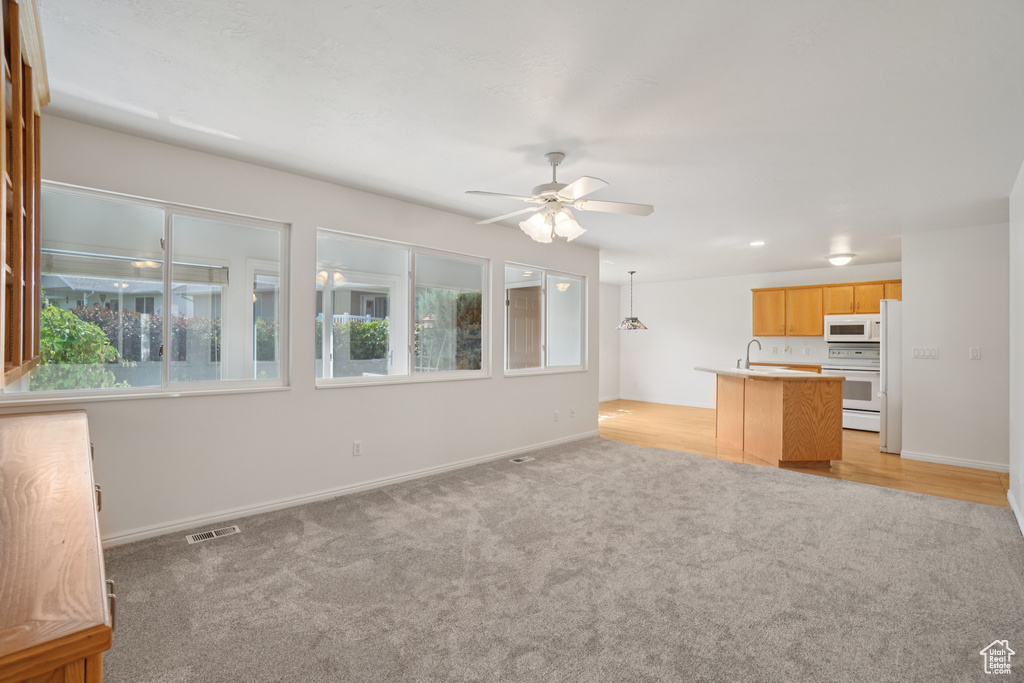 Unfurnished living room featuring light colored carpet and a ceiling fan