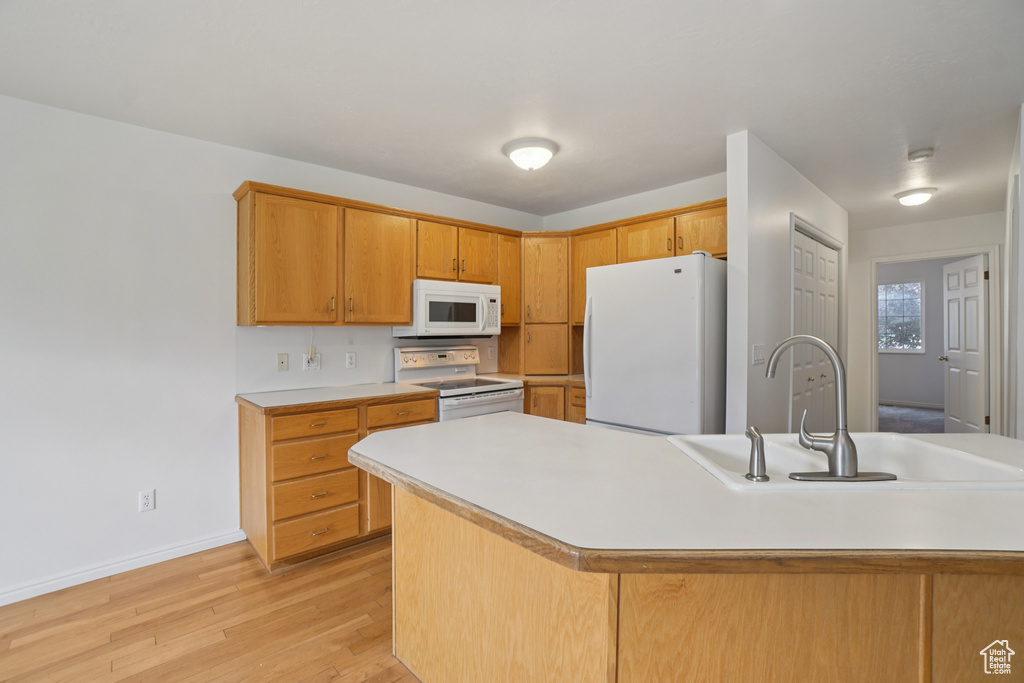 Kitchen with white appliances, light countertops, and light wood finished floors