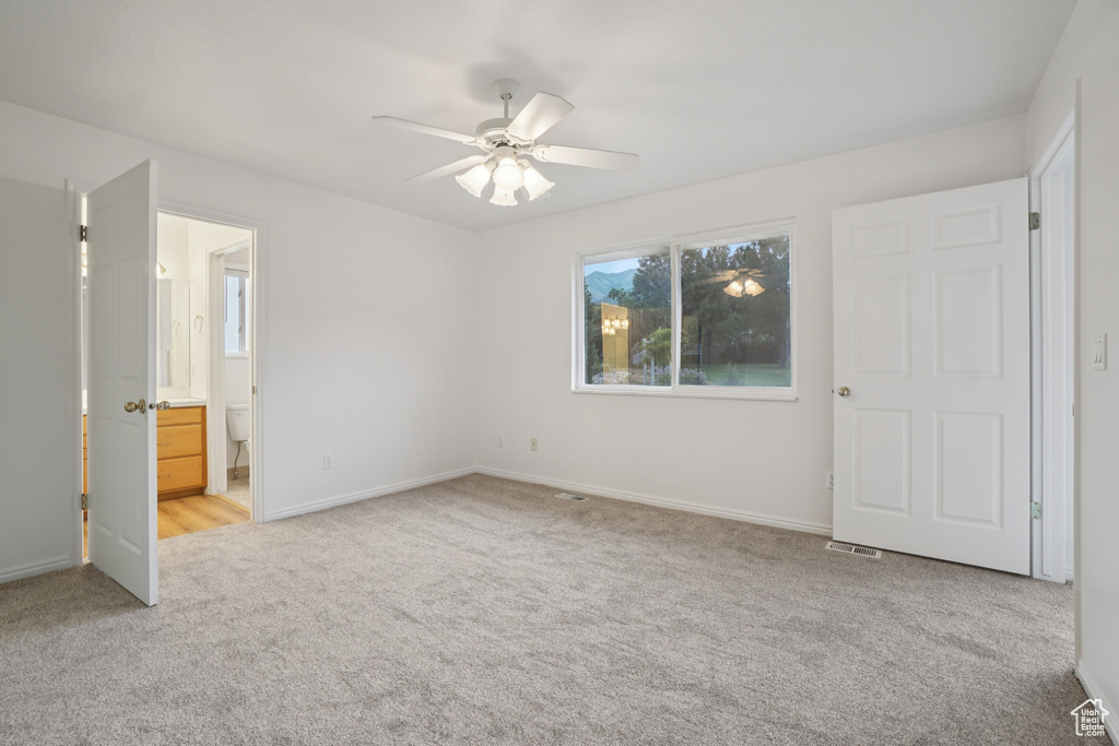 Unfurnished bedroom with light carpet, ceiling fan, and ensuite bathroom
