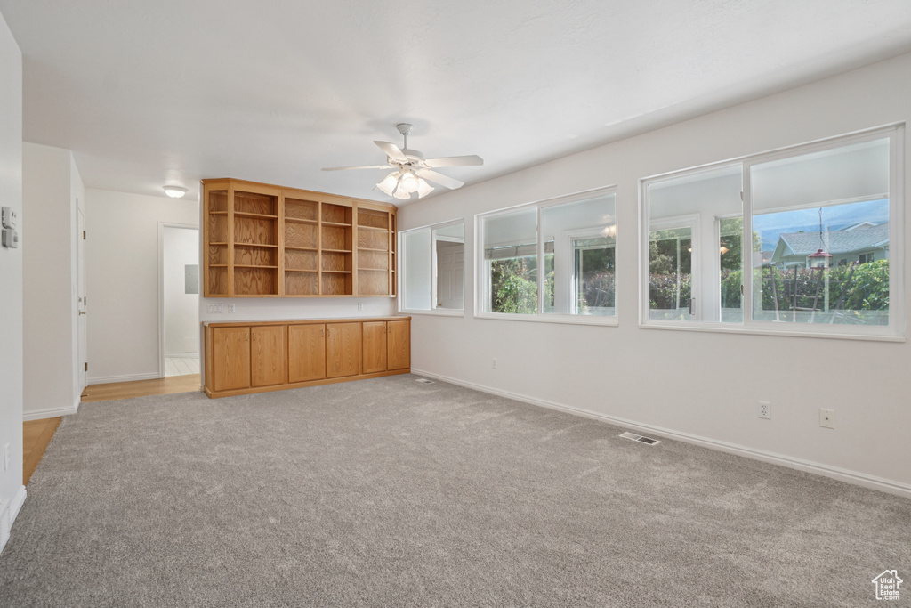 Unfurnished living room with a ceiling fan and light colored carpet