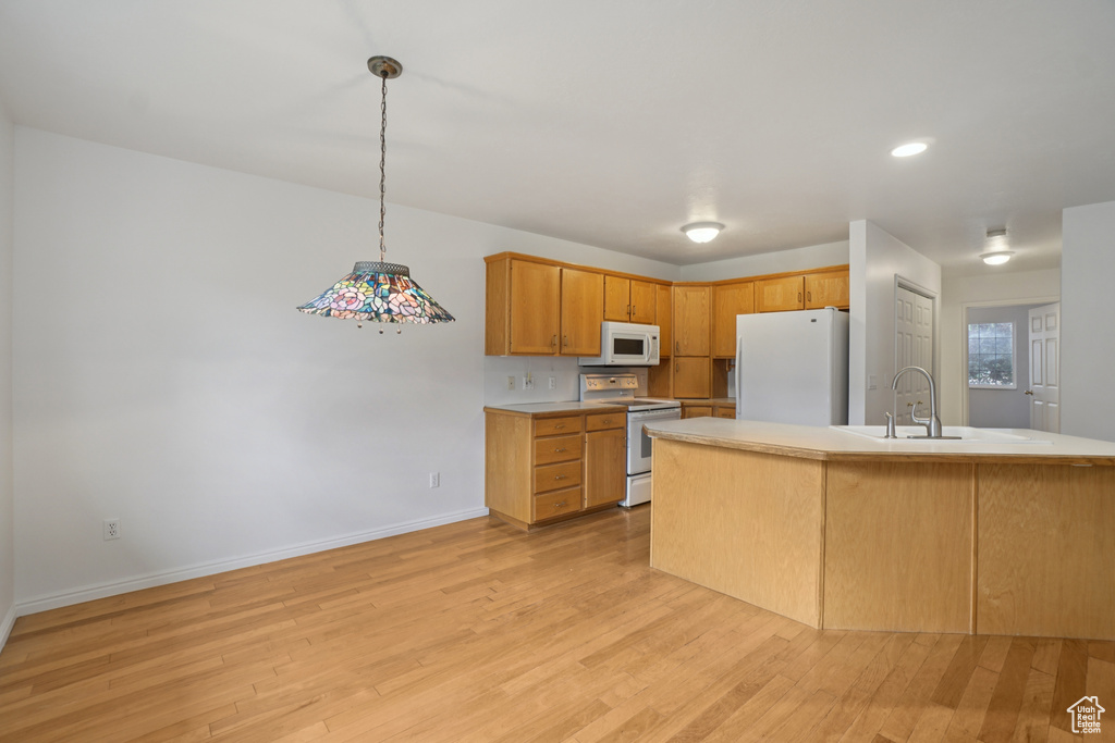 Kitchen featuring white appliances, light wood-type flooring, light countertops, decorative light fixtures, and recessed lighting