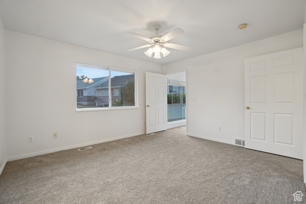 Empty room featuring carpet flooring and a ceiling fan