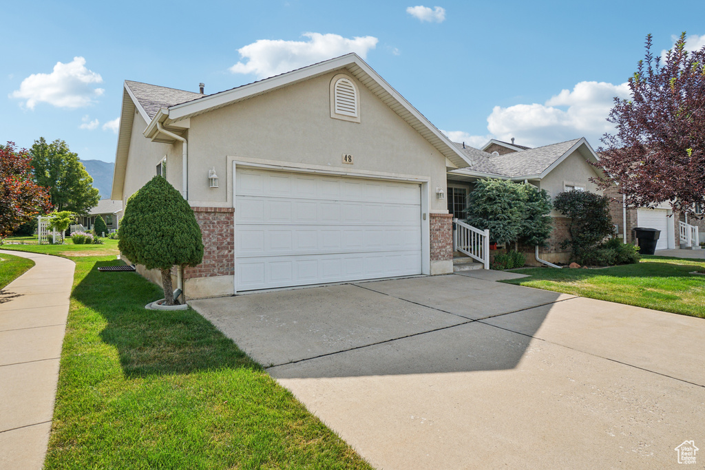 View of front of property featuring a garage, brick siding, and concrete driveway