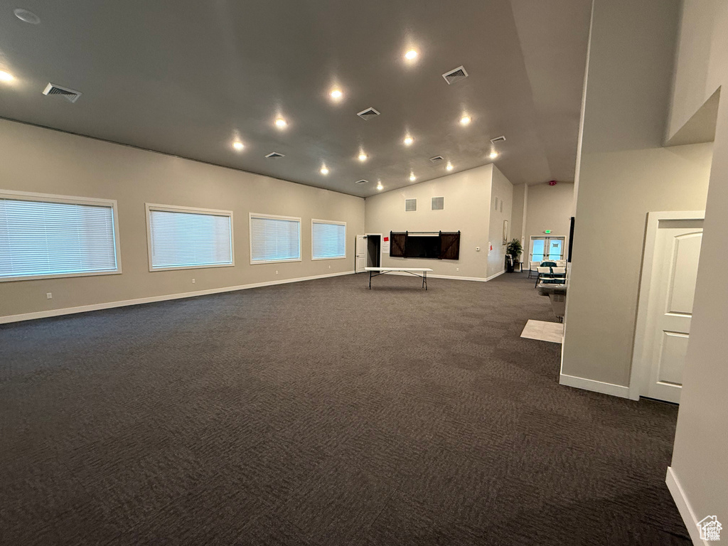 Unfurnished living room with dark colored carpet and vaulted ceiling