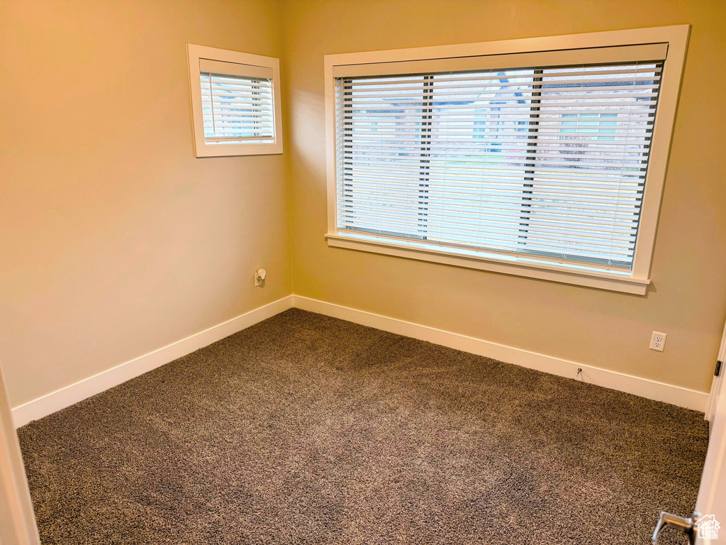 Unfurnished room featuring dark carpet and baseboards