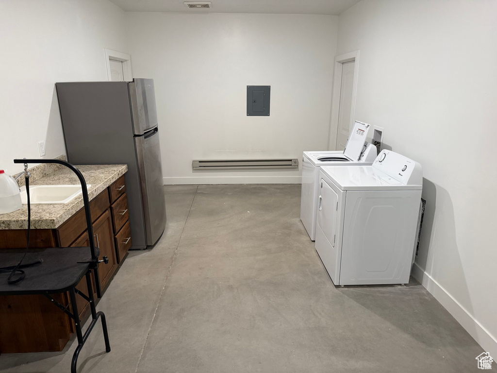 Washroom with washer and clothes dryer, a baseboard radiator, and electric panel