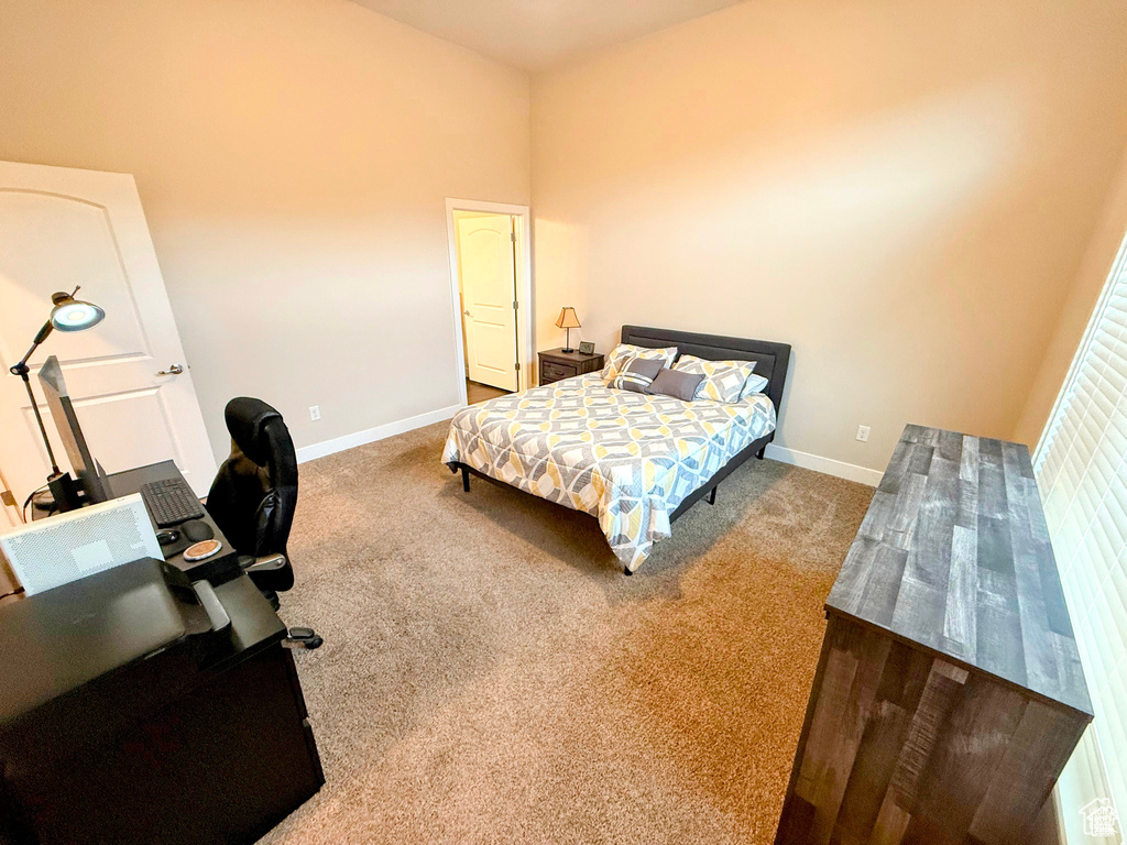Carpeted bedroom with baseboards and an office area