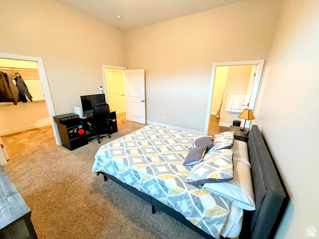Bedroom featuring carpet floors, a towering ceiling, and an office area