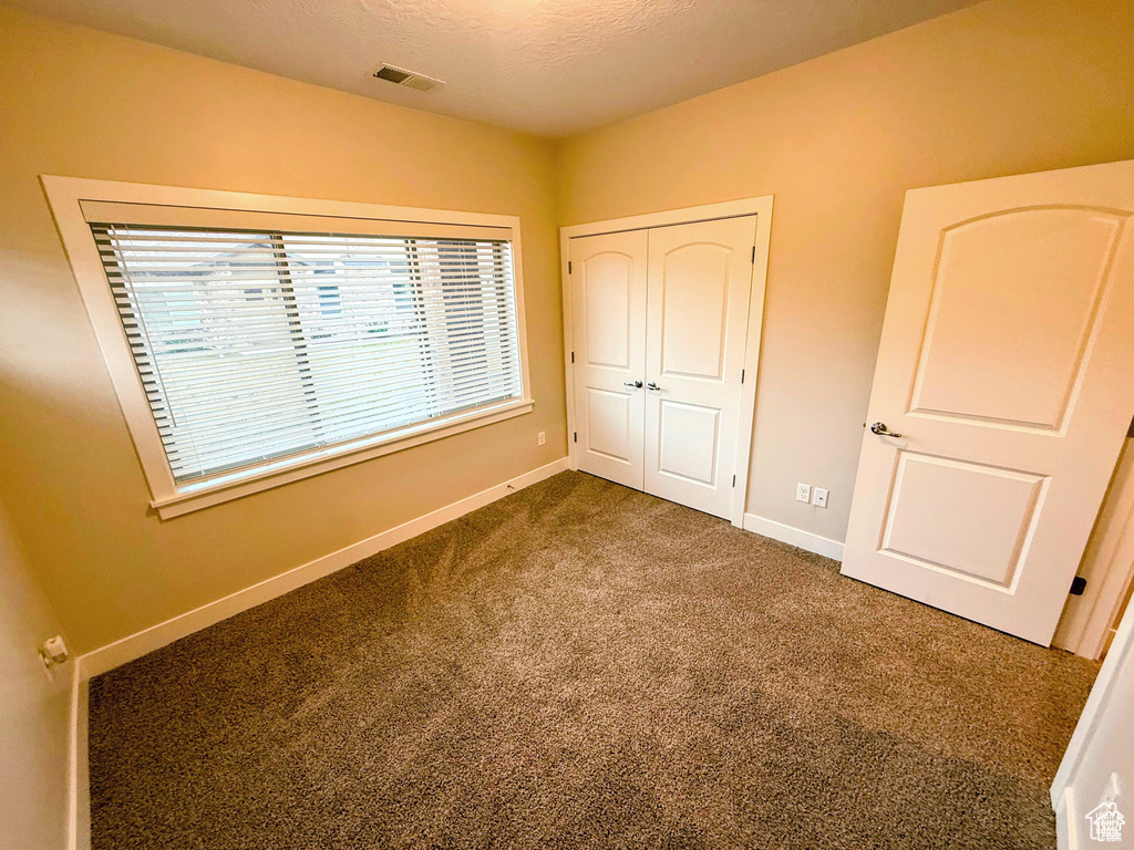 Unfurnished bedroom with dark carpet and a closet
