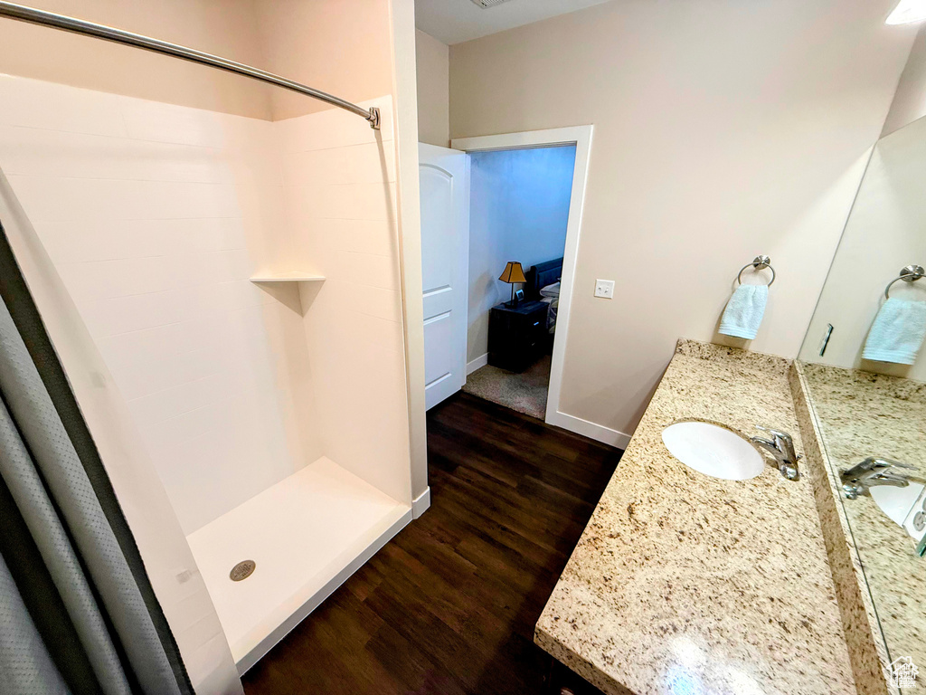 Full bathroom with wood finished floors, a shower stall, and vanity