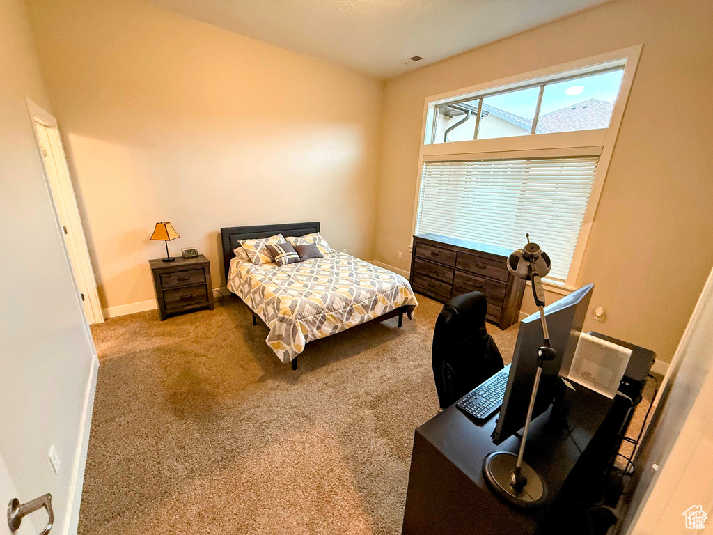 Carpeted bedroom featuring an office area and baseboards