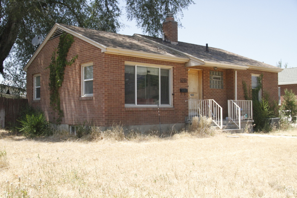 View of front of home with brick siding and a chimney