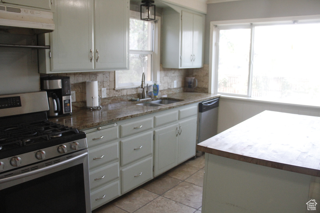 Kitchen featuring stainless steel appliances, under cabinet range hood, decorative backsplash, and plenty of natural light