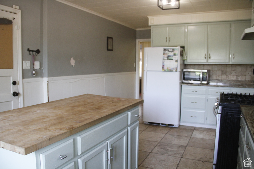 Kitchen featuring stainless steel appliances, crown molding, a center island, backsplash, and butcher block counters