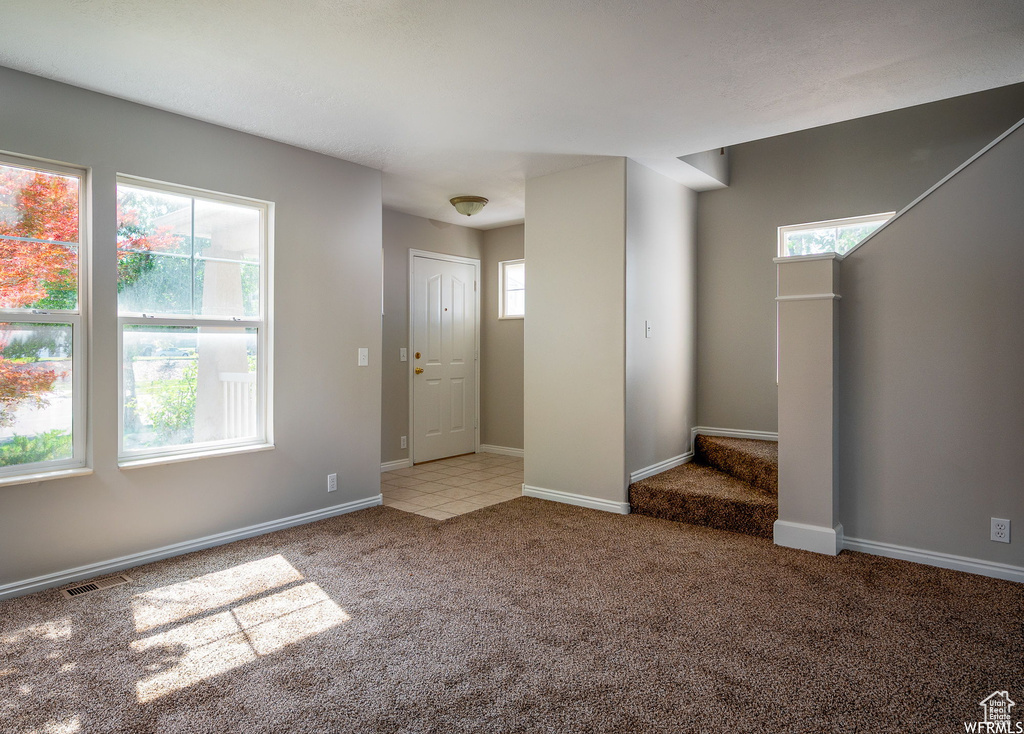 Carpeted foyer featuring stairway and baseboards