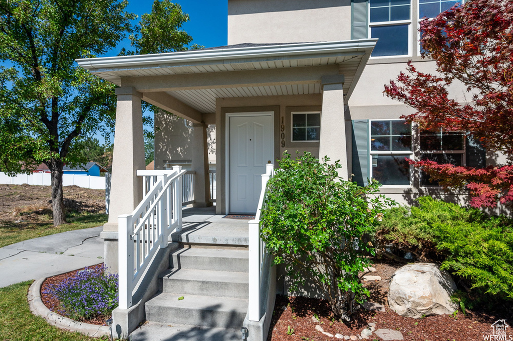 Entrance to property with stucco siding and a porch