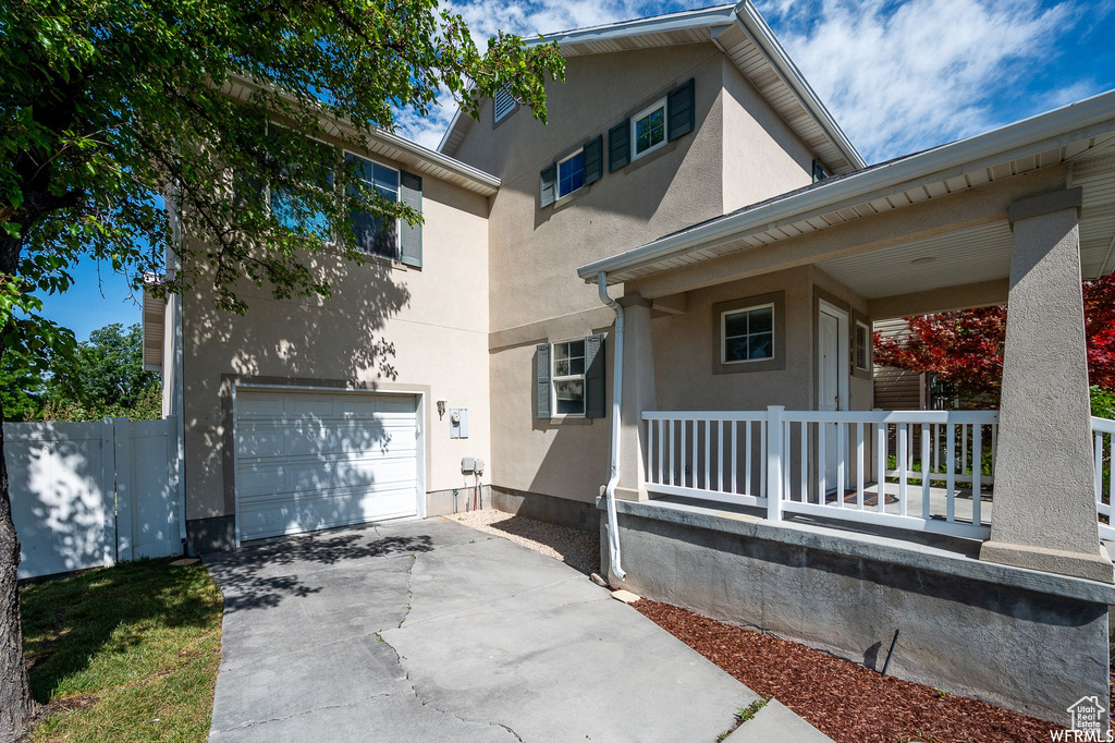 View of front of property featuring a porch, an attached garage, driveway, and stucco siding