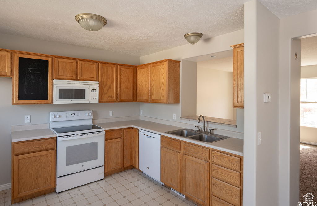 Kitchen with white appliances, light countertops, light floors, and a textured ceiling