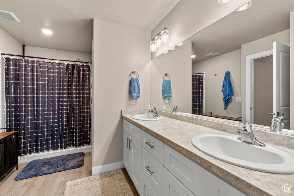 Bathroom with double vanity, wood finished floors, and a shower with curtain