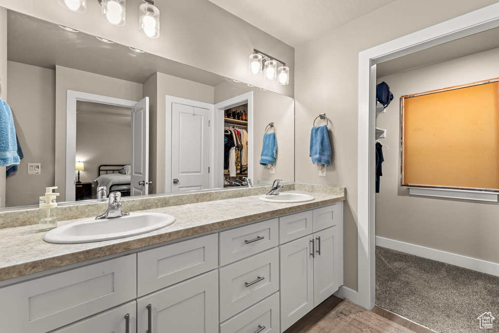 Bathroom with double vanity, connected bathroom, and a walk in closet