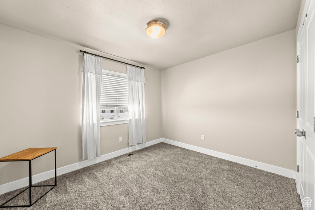 Carpeted spare room featuring baseboards