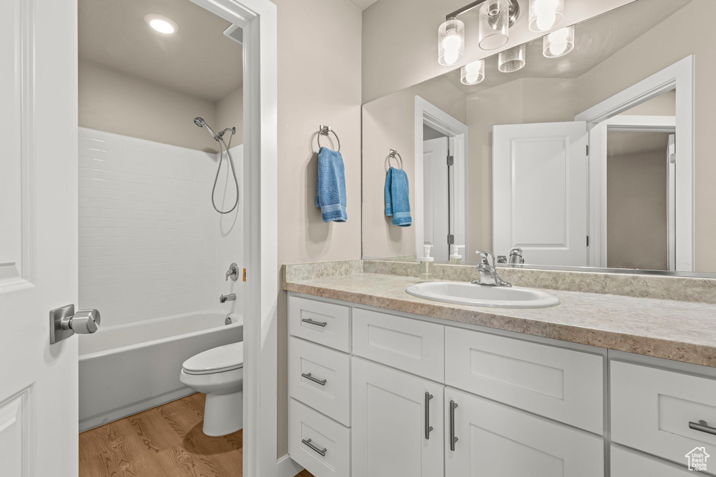 Bathroom featuring wood finished floors, vanity, and  shower combination