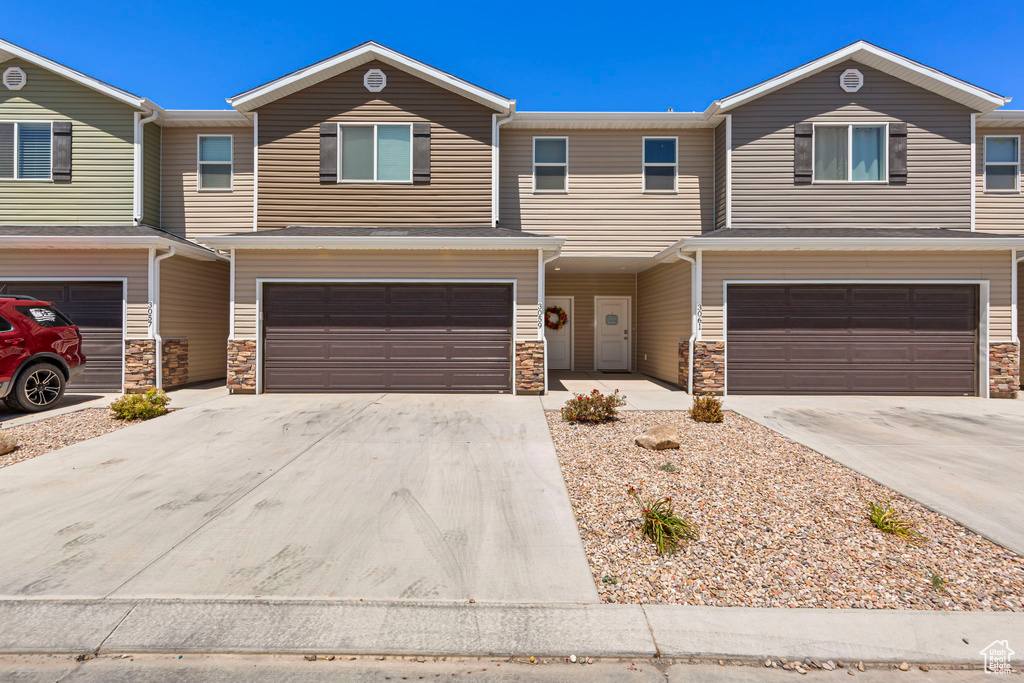 View of front of home featuring stone siding, a garage, and concrete driveway