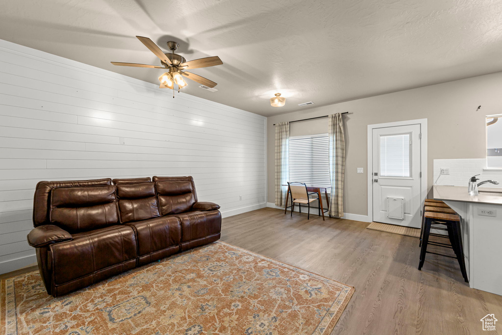 Living room with wood finished floors, a ceiling fan, and wood walls