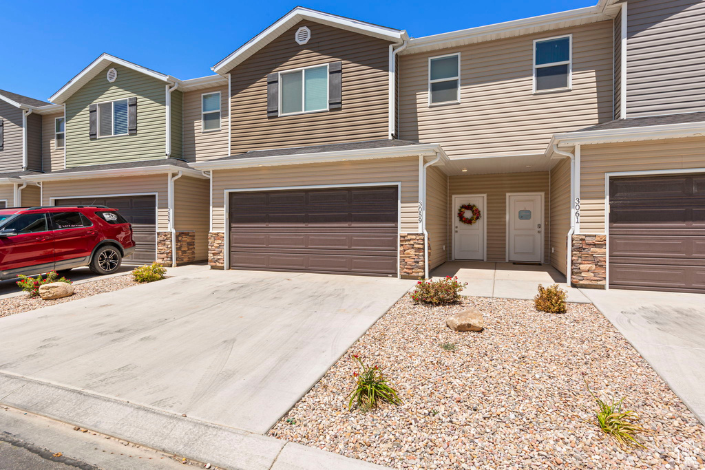 View of front of house with concrete driveway, stone siding, and a garage
