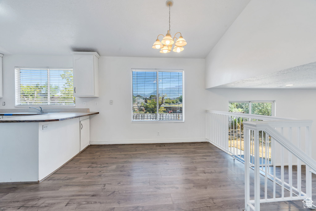 Kitchen featuring a chandelier, dark wood finished floors, white cabinets, vaulted ceiling, and decorative light fixtures