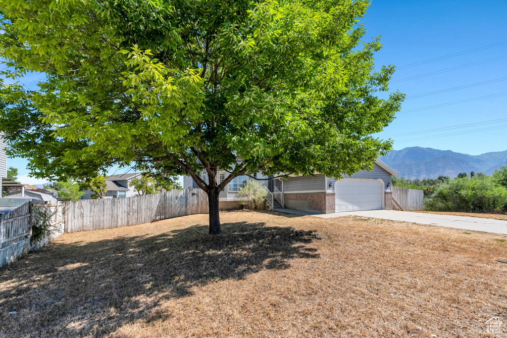 View of yard with concrete driveway, a mountain view, and a garage