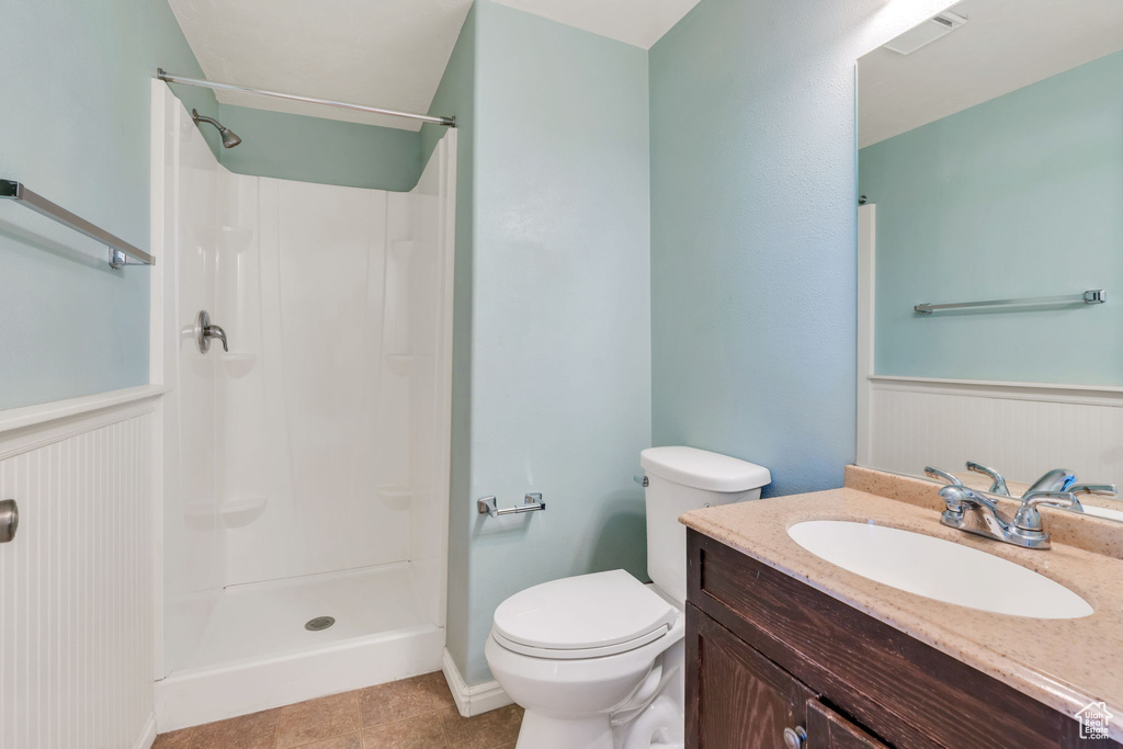 Full bathroom with wainscoting, vanity, a shower, and tile patterned flooring