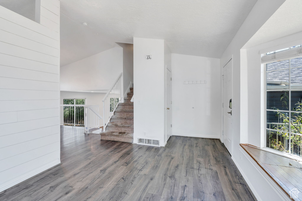 Entryway with wood finished floors, stairs, and vaulted ceiling