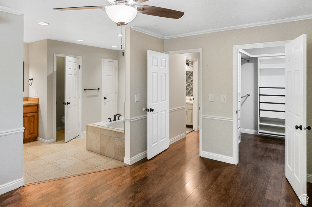 Unfurnished bedroom with a spacious closet, light wood-type flooring, recessed lighting, crown molding, and connected bathroom