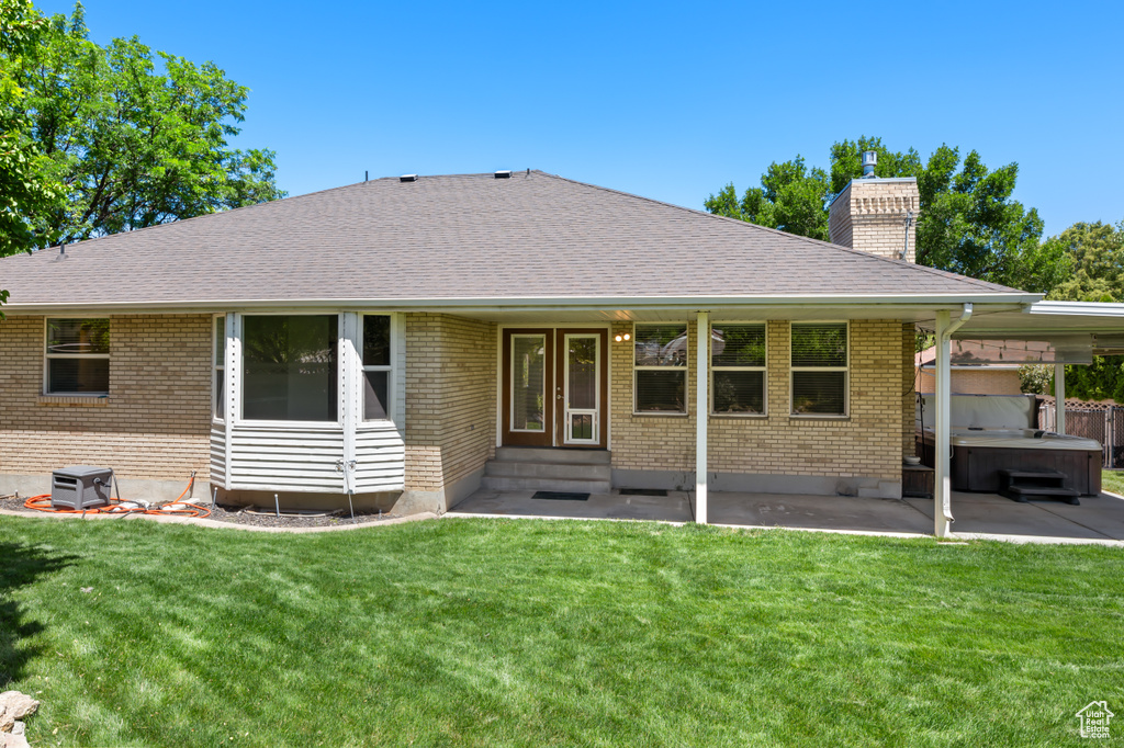 Back of property with a hot tub, entry steps, a patio area, and brick siding