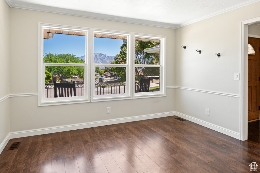 Empty room featuring crown molding, dark wood finished floors, and a mountain view