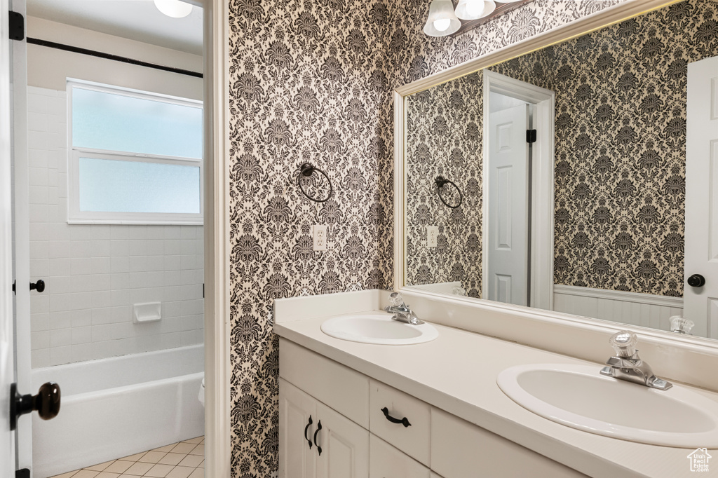 Bathroom featuring double vanity, wallpapered walls, tile patterned floors, and shower / tub combination