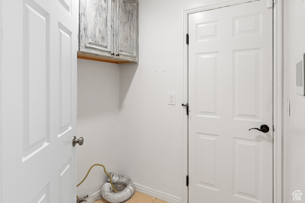 Laundry area with cabinet space and light tile patterned floors