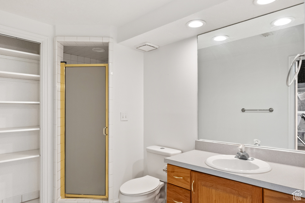 Full bath with a walk in closet, vanity, a shower stall, and recessed lighting