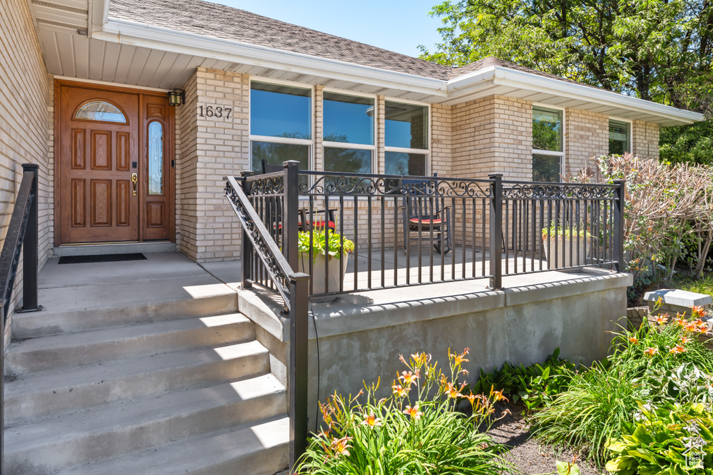 Entrance to property with brick siding and roof with shingles