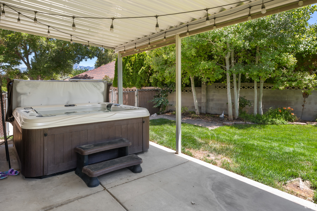 Fenced backyard with a hot tub and a patio